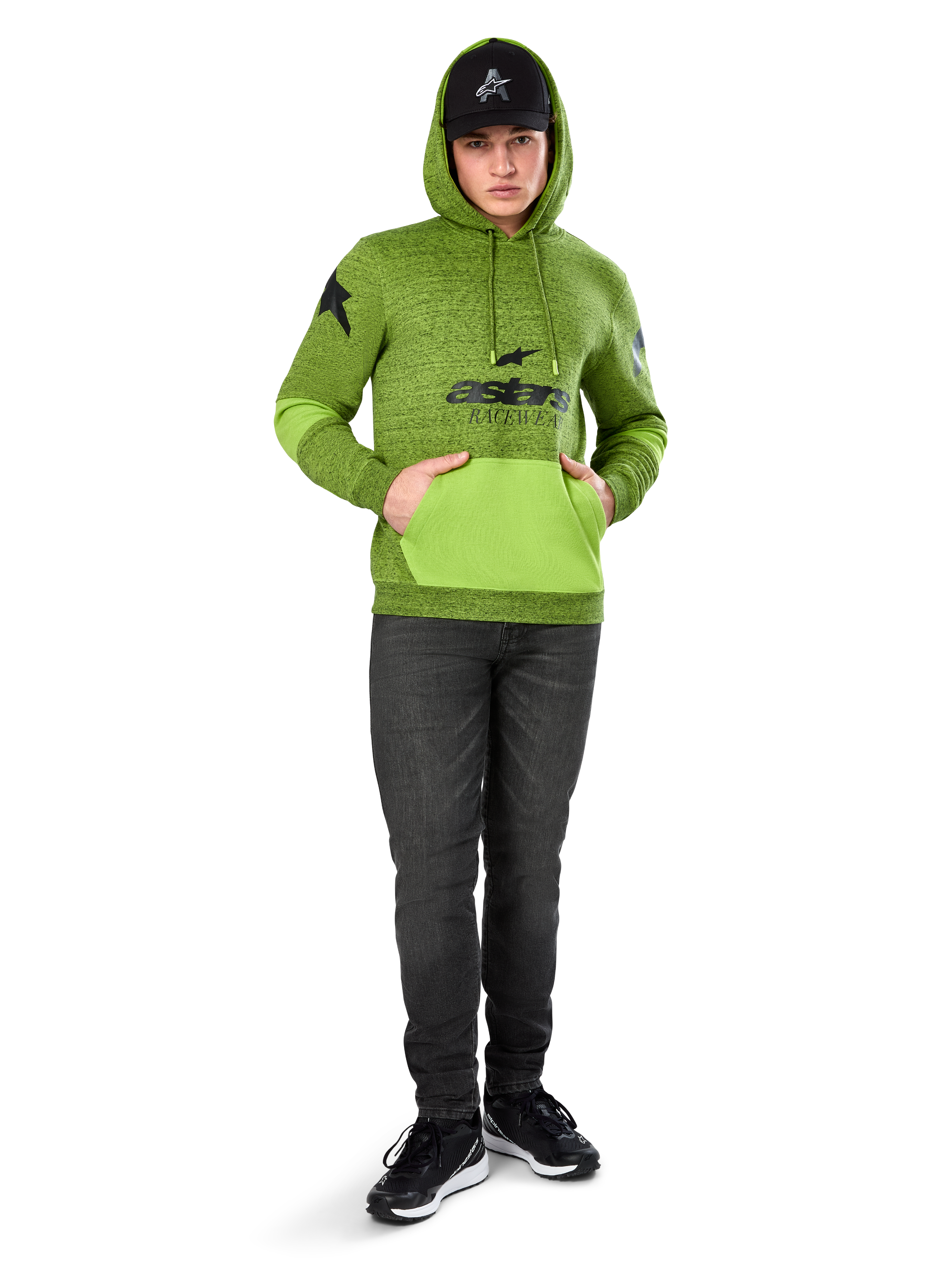 Alpinestars Perpetuate Hoodie, polarowa bluza w kolorze limonkowej zieleni (melanż) z kontrastową jaskrawozieloną kieszenią kangurka i panelami na rękawach, czarna grafika 'astars' z przodu, stylizowana z czarną czapką i ciemnymi dżinsami, codzienna odzież streetwearowa inspirowana sportami motorowymi