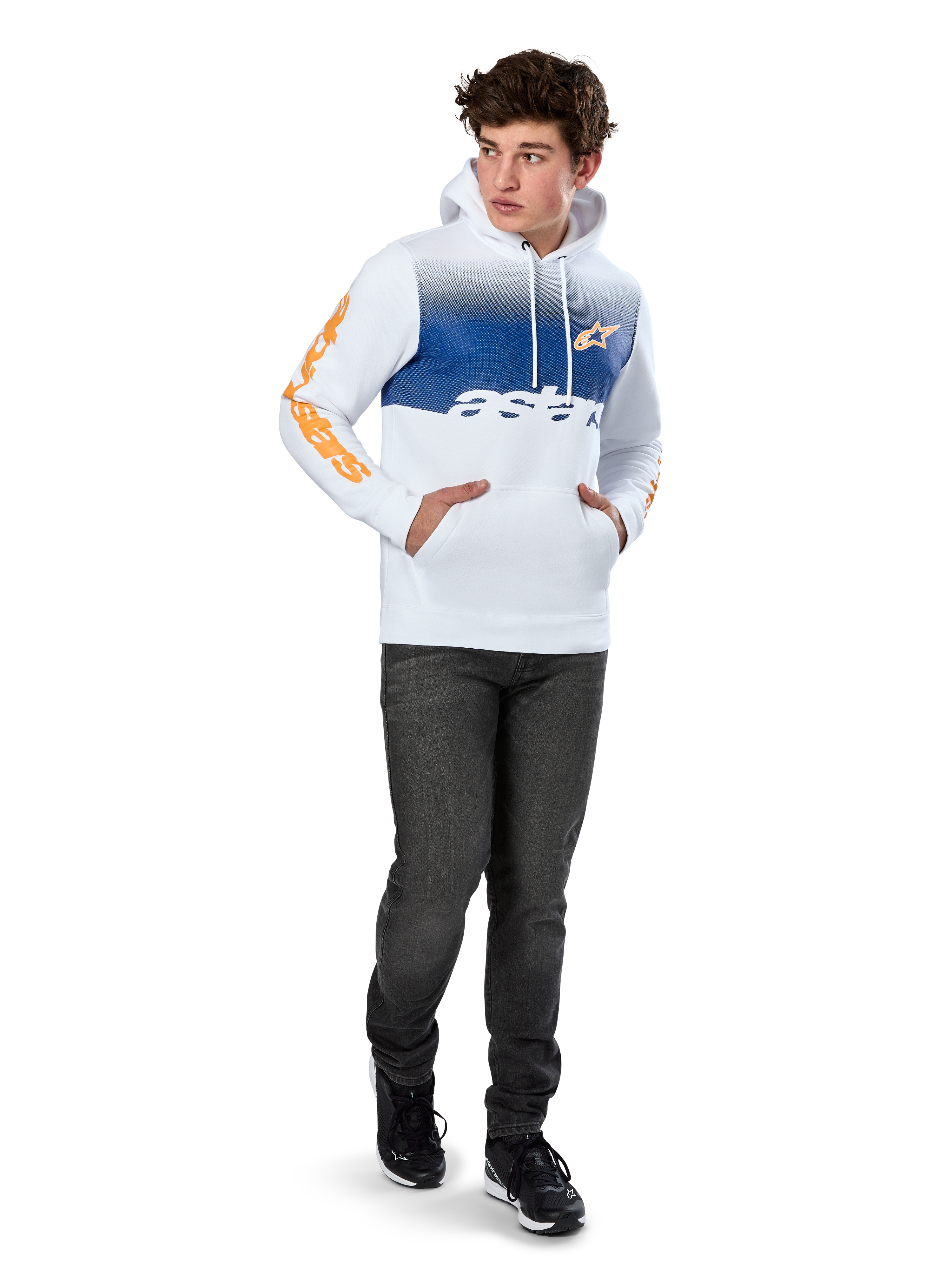Alpinestars Specter Hoodie, biała bluza polarowa wkładana przez głowę z niebieskim cieniowanym nadrukiem, pomarańczowe logo HD z przodu i napisy na rękawach, z kieszenią typu kangurka i kapturem ściąganym sznurkiem, noszona z ciemnymi dżinsami w swobodnym stylu inspirowanym sportami motorowymi