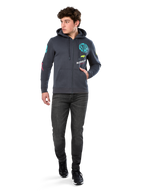Alpinestars Variegate Hoodie, polarowa bluza z kapturem zapinana na zamek, kolor ciemnoszary (Gunmetal), noszona przez modela z czarnymi dżinsami i sneakersami, turkusowy napis „ASTARS” oraz kolorowe grafiki na rękawach i klatce piersiowej, codzienna odzież uliczna inspirowana sportami motorowymi