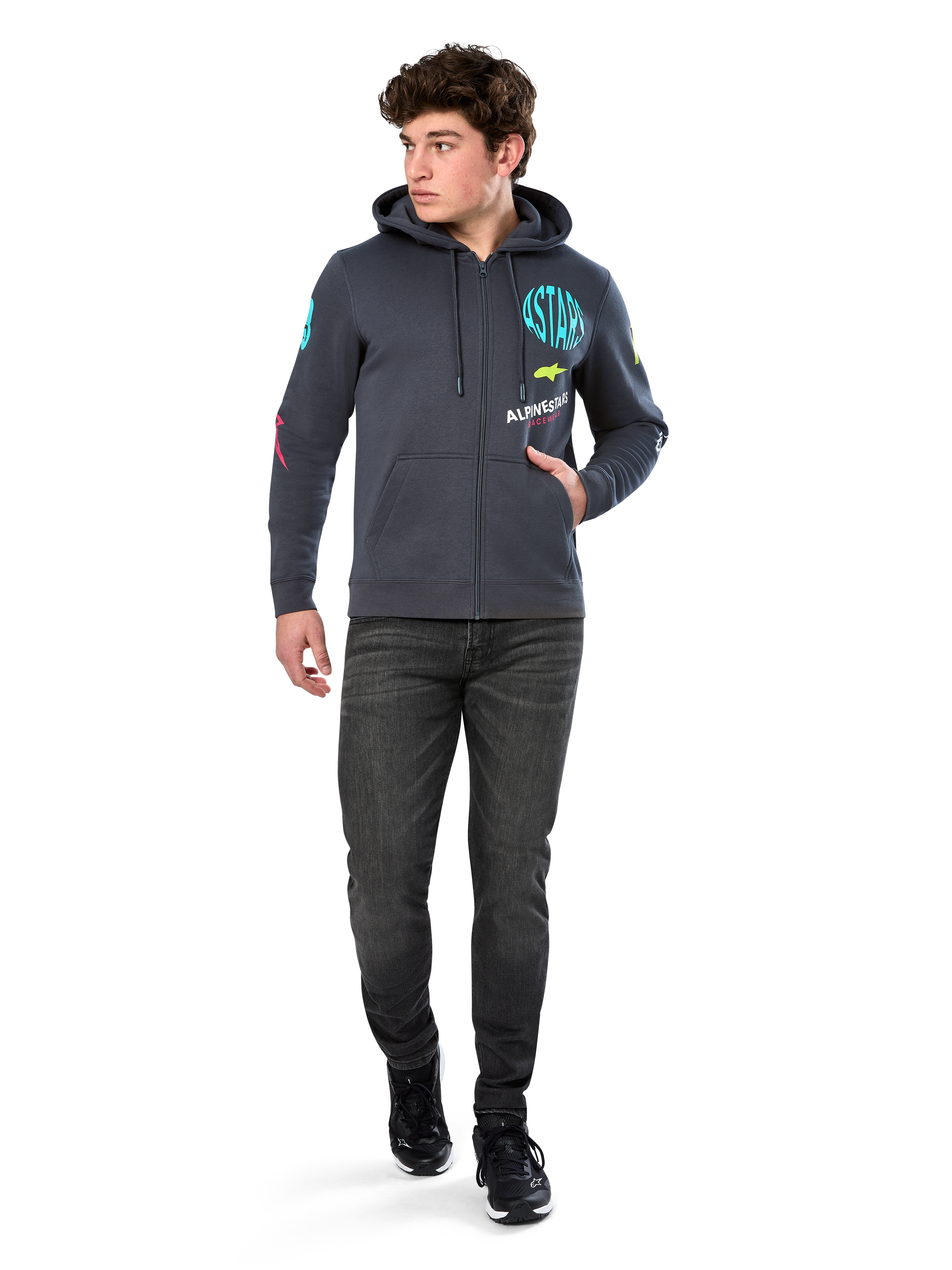 Alpinestars Variegate Hoodie, polarowa bluza z kapturem zapinana na zamek, kolor ciemnoszary (Gunmetal), noszona przez modela z czarnymi dżinsami i sneakersami, turkusowy napis „ASTARS” oraz kolorowe grafiki na rękawach i klatce piersiowej, codzienna odzież uliczna inspirowana sportami motorowymi