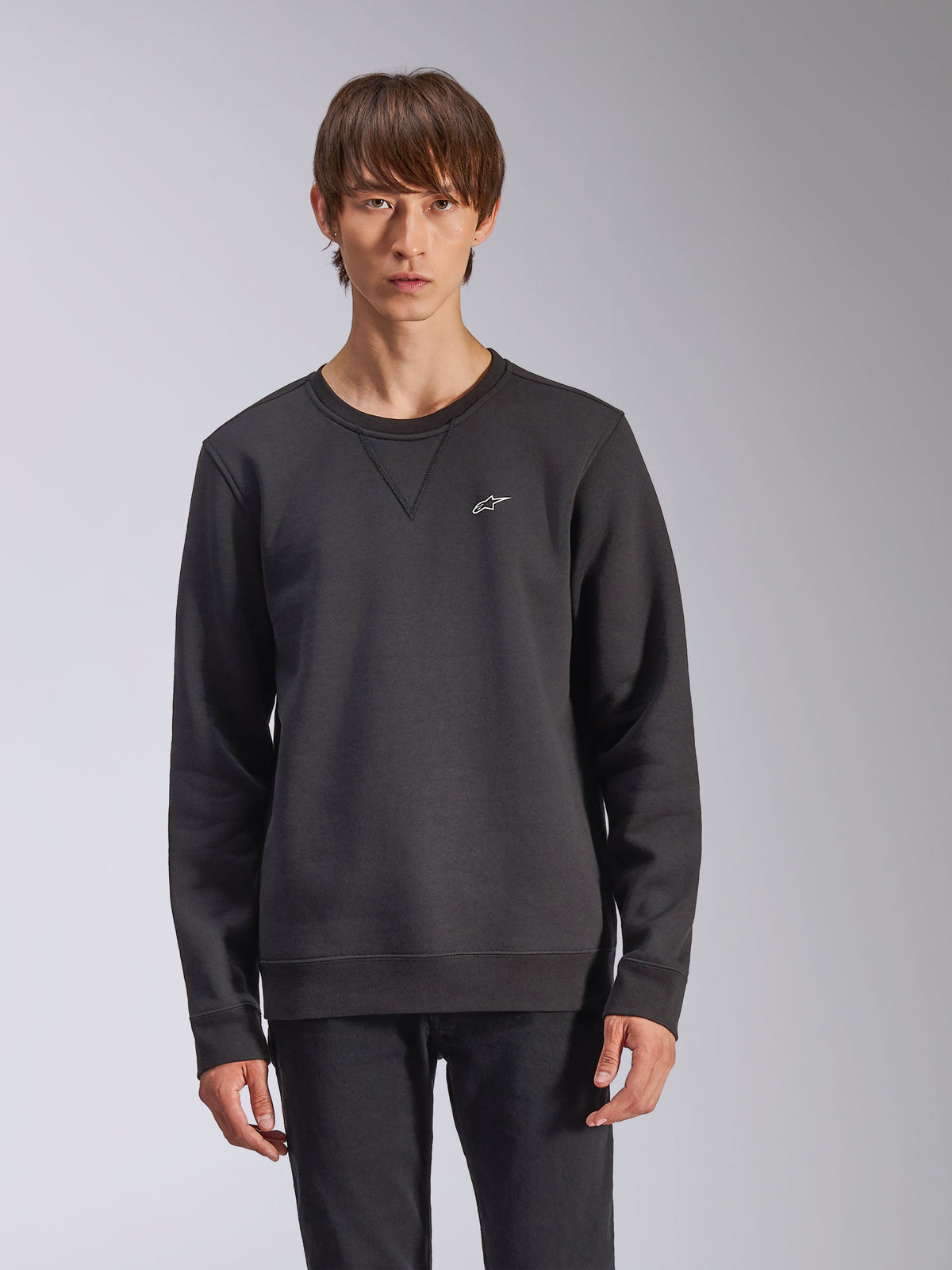 Alpinestars Positive Crew Sweatshirt, czarna bluza, małe białe logo gwiazdy Alpinestars na piersi, przeszycie V-stitch przy dekolcie, ściągacze przy mankietach i na dole, codzienna odzież uliczna inspirowana sportami motorowymi
