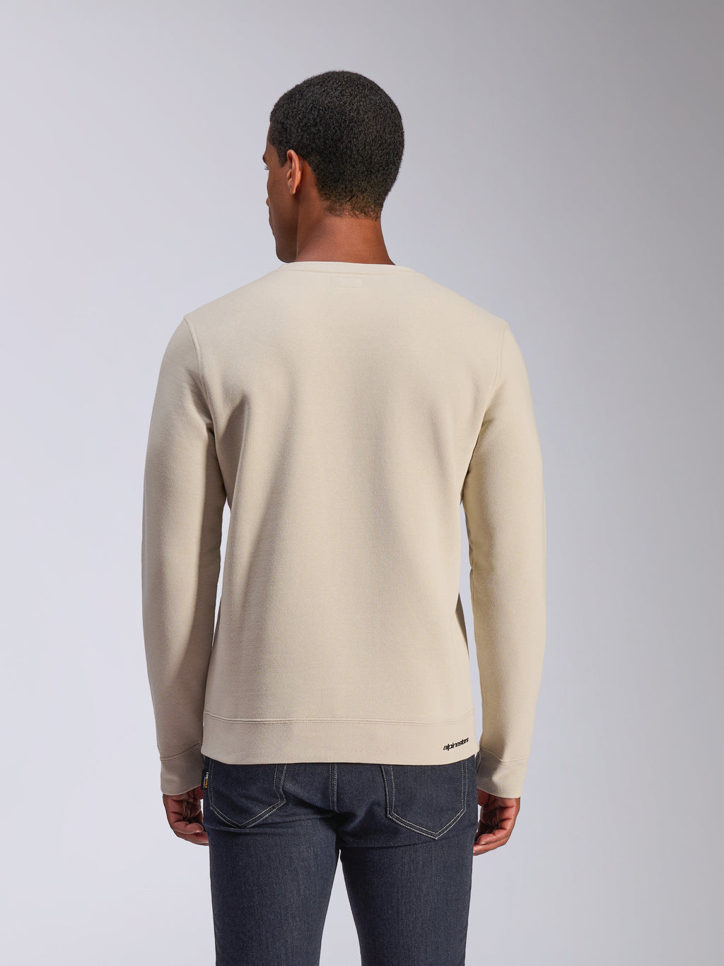 Alpinestars Positive Crew, bluza typu crewneck w kolorze Off White, widok z tyłu, casualowy streetwear w stylu motorsport, ściągacze na dole i przy mankietach, małe logo Alpinestars na dolnym ściągaczu