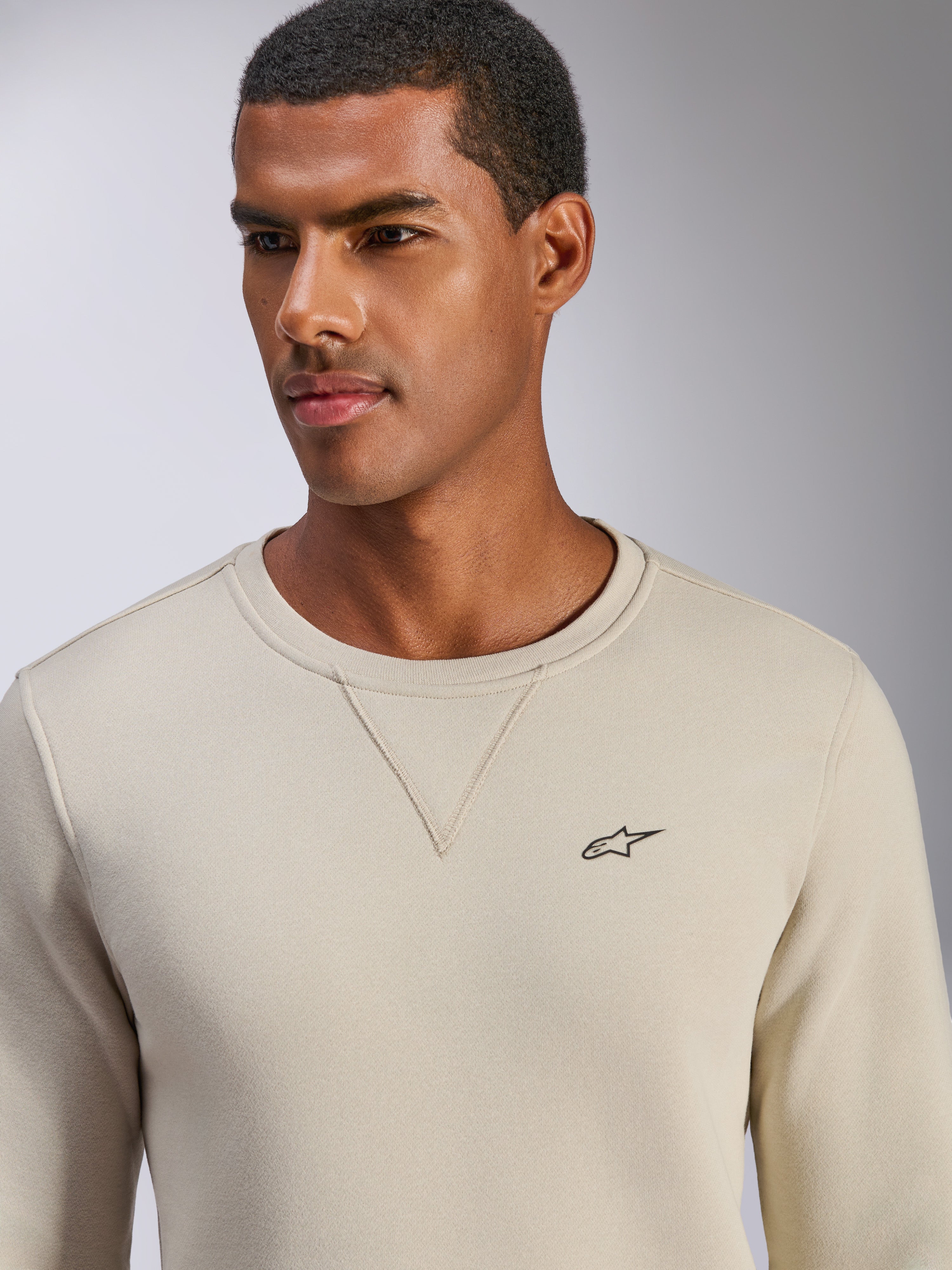 Alpinestars Positive Crew Sweatshirt, bluza typu crewneck w kolorze złamanej bieli, małe czarne logo z gwiazdą na piersi, detal z przeszyciem V przy dekolcie, codzienna odzież lifestylowa inspirowana sportami motorowymi