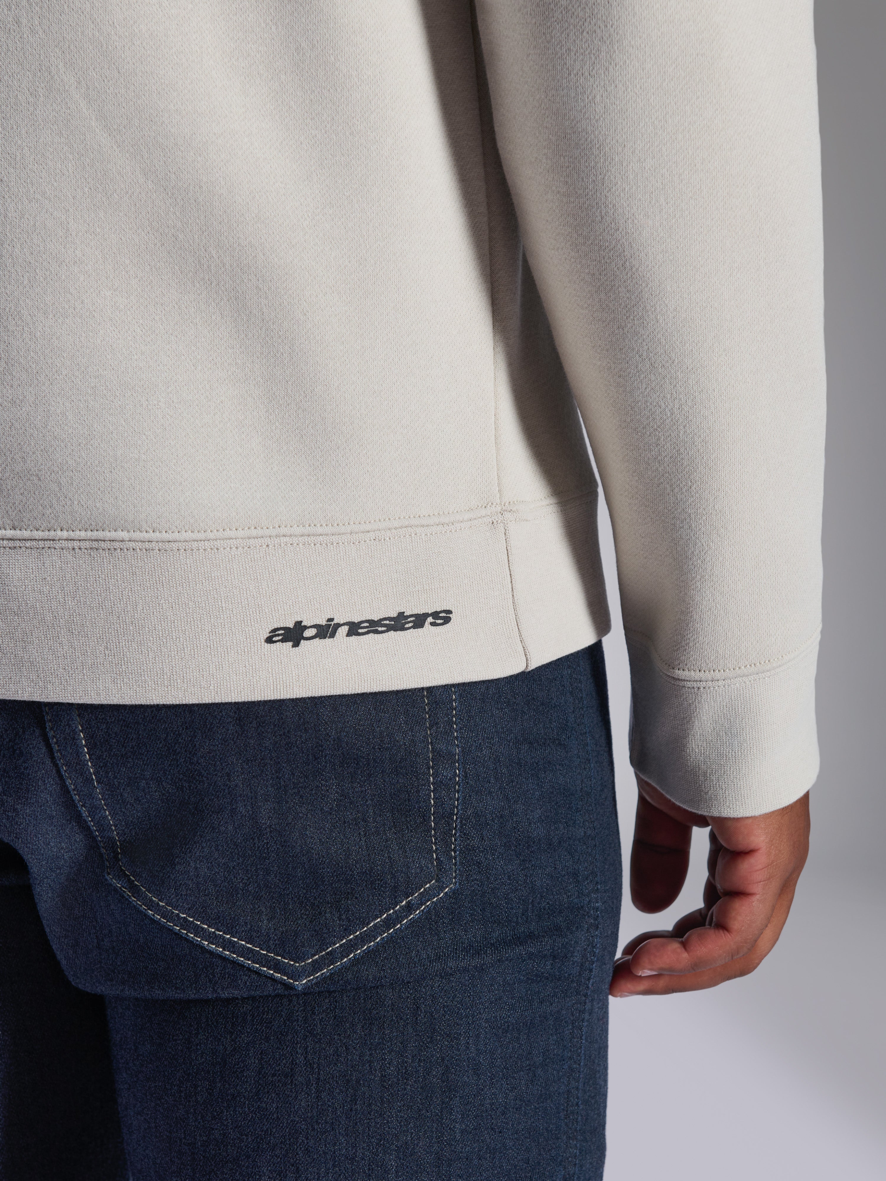 Bluza Alpinestars Positive Crew, Off White, zbliżenie na prążkowany dół i mankiet, z małym czarnym logo Alpinestars, codzienna odzież inspirowana sportami motorowymi