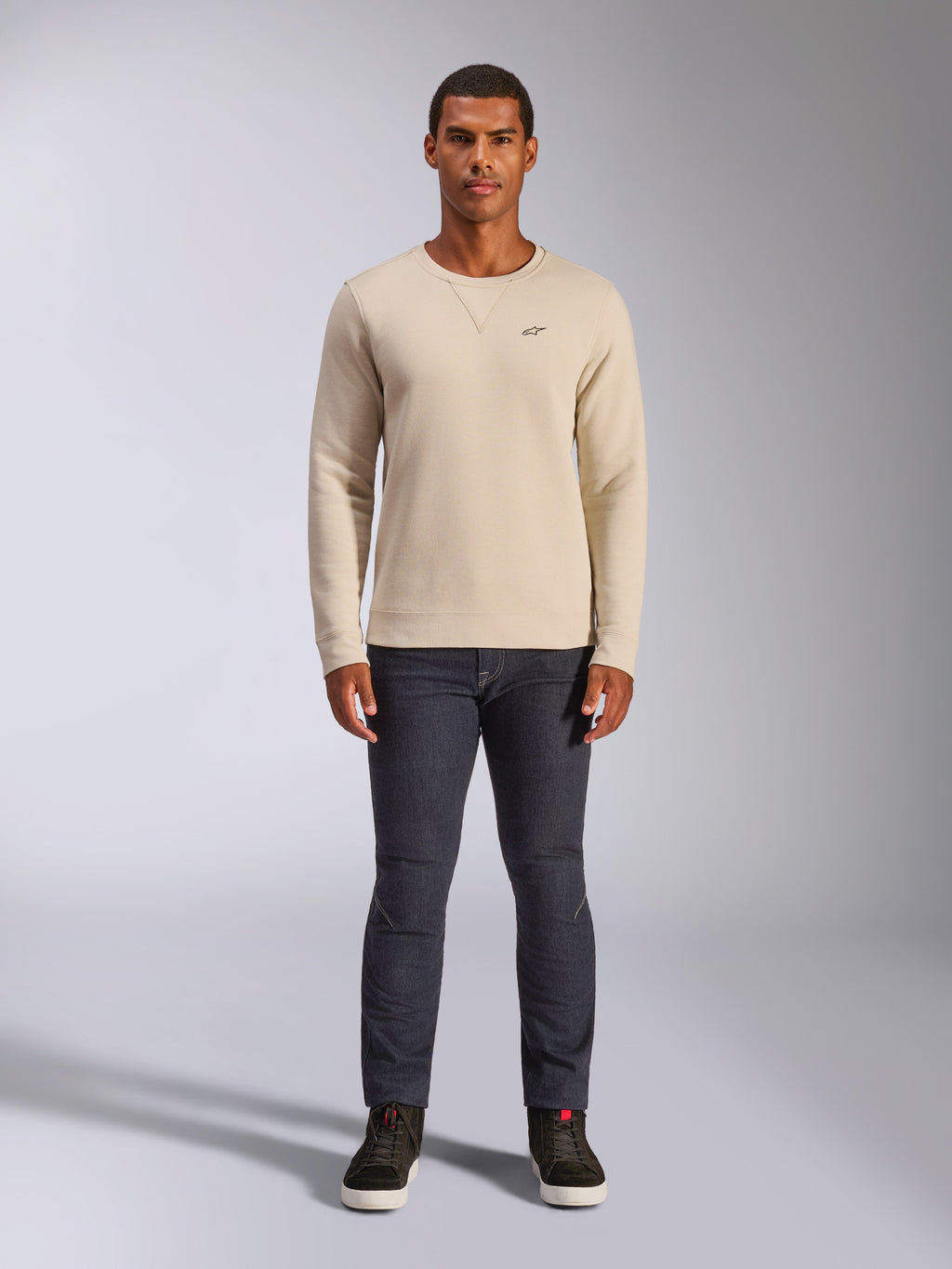 Alpinestars Positive Crew, bluza typu crewneck w kolorze Off White, małe czarne logo na piersi, ściągacze przy mankietach i na dole, trójkątne przeszycie przy dekolcie, codzienny motorsportowy streetwear noszony z ciemnymi dżinsami