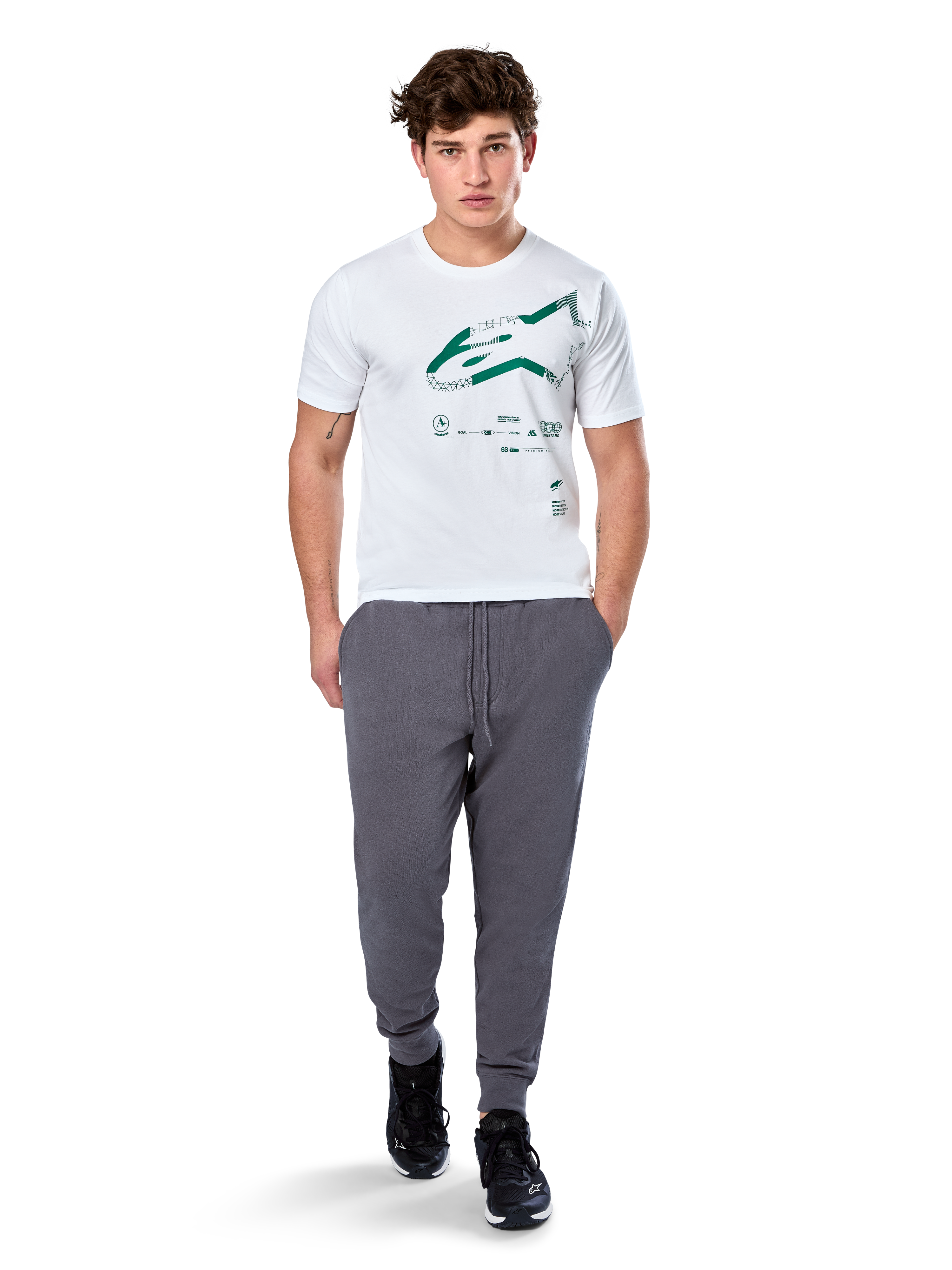 Alpinestars Geografica CSF Tee, koszulka z krótkim rękawem, biała, zielone logo Astars z geograficzną grafiką multi-tech, noszona z szarymi spodniami dresowymi i czarnymi sneakersami, codzienny motorsportowy styl streetwear