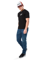 Alpinestars Formulate Csf Tee, koszulka z krótkim rękawem, czarna z białym logo Astars na klatce piersiowej, prezentowana przez modela w niebieskich jeansach, bordowo-białej czapce z daszkiem i czarnych sneakersach, codzienna odzież streetwearowa inspirowana sportami motorowymi