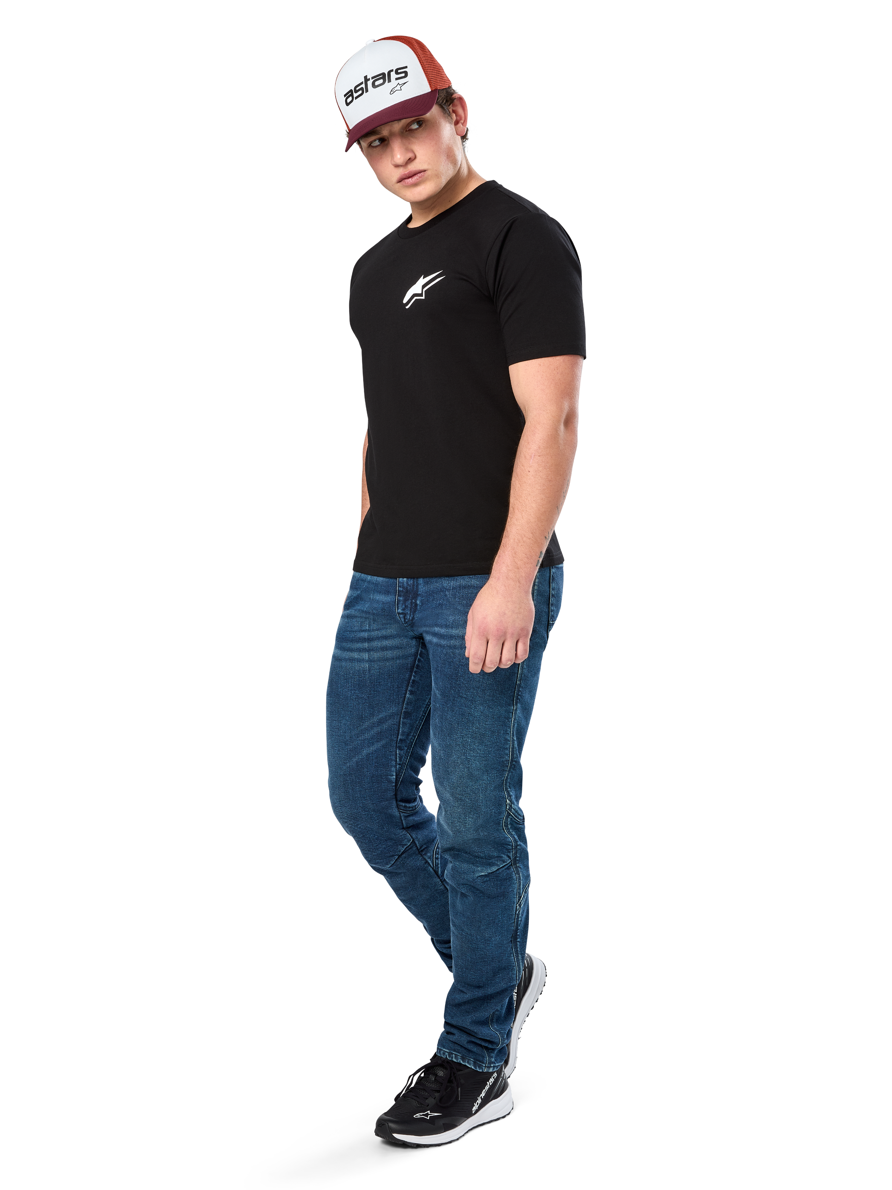 Alpinestars Formulate Csf Tee, koszulka z krótkim rękawem, czarna z białym logo Astars na klatce piersiowej, prezentowana przez modela w niebieskich jeansach, bordowo-białej czapce z daszkiem i czarnych sneakersach, codzienna odzież streetwearowa inspirowana sportami motorowymi