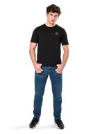 Alpinestars Dot Carbon CSF Tee, koszulka z krótkim rękawem, czarna, małe okrągłe logo Astars Dot na piersi, zestawiona z niebieskimi jeansami i czarnymi sneakersami, codzienna odzież streetwearowa w stylu motorsportowym