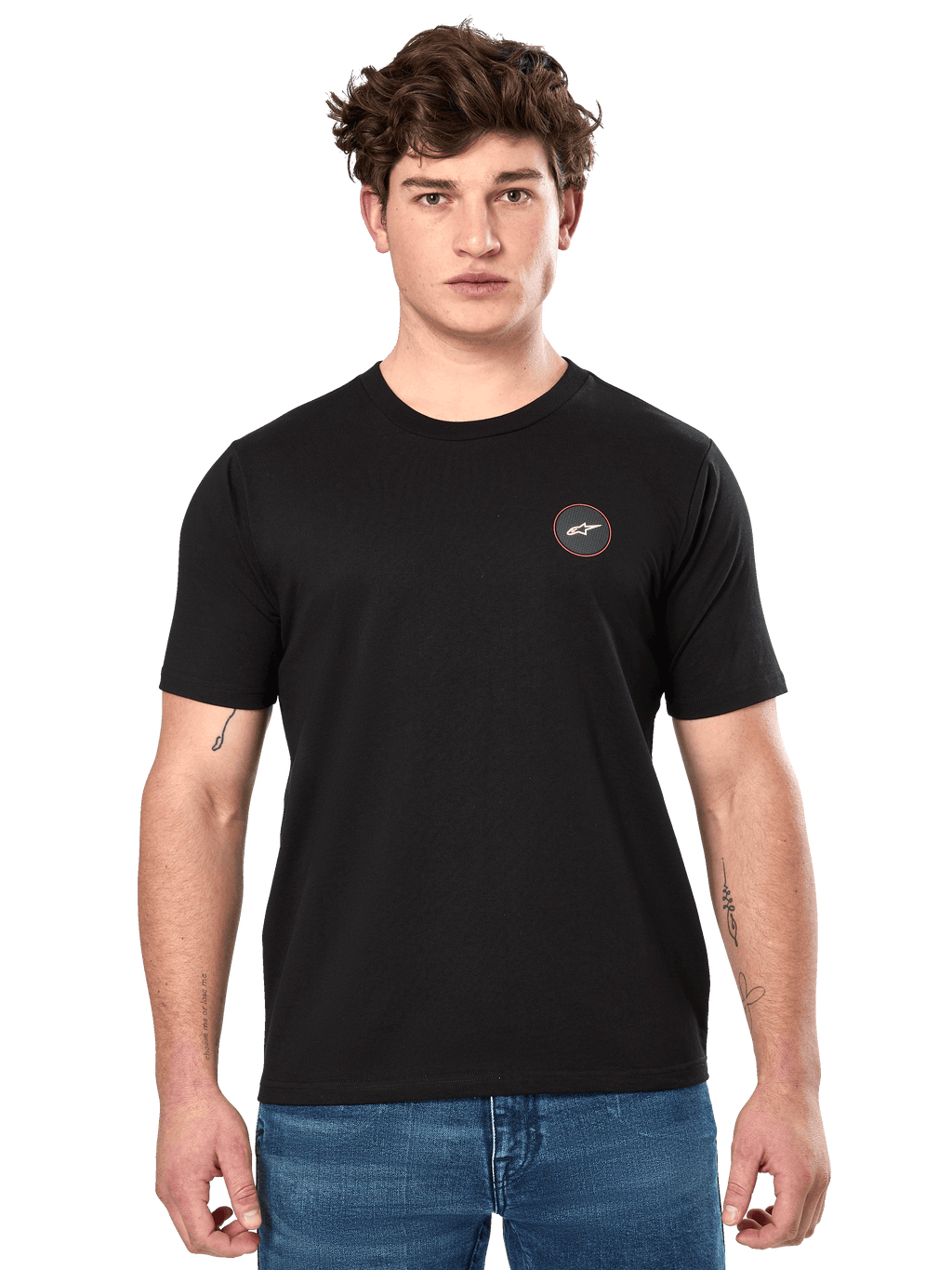 Alpinestars Dot Carbon CSF Tee, czarna koszulka z krótkim rękawem, małe okrągłe logo na piersi z białą gwiazdą Astar i czerwoną obwódką, noszona przez modela w niebieskich dżinsach, codzienna odzież motorsportowa typu streetwear