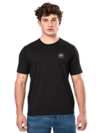 Alpinestars Dot Carbon CSF Tee, czarna koszulka z krótkim rękawem, małe okrągłe logo na piersi z białą gwiazdą Astar i czerwoną obwódką, noszona przez modela w niebieskich dżinsach, codzienna odzież motorsportowa typu streetwear