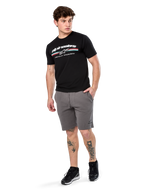 Alpinestars Prevail Csf Tee, koszulka z krótkim rękawem, czarna, białe logo Alpinestars z trójkolorowym paskiem w stylu paddock, noszona z szarymi szortami i czarnymi sneakersami, codzienna odzież streetwearowa w stylu motorsportowym