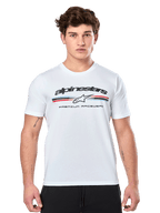 Alpinestars Prevail CSF Tee, biała koszulka z krótkim rękawem, z przodu trójkolorowe paski w stylu paddock z czerwonymi i niebieskimi akcentami, czarne logo Alpinestars i napis „Premium Racewear”, model męski, codzienna odzież motorsportowa