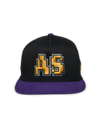 Alpinestars Franchise Hat, czarno-fioletowa czapka z płaskim daszkiem, usztywniona korona z fioletowym daszkiem i górnym guzikiem, złote haftowane logo 3D „AS” z przodu, casualowy styl streetwearowy inspirowany motorsportem