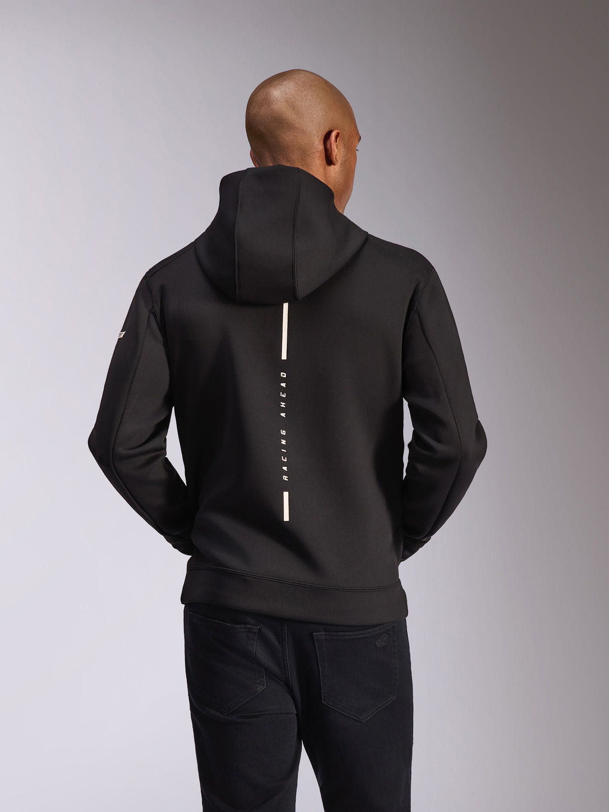 Alpinestars Insight Hoodie, widok z tyłu, czarna, pionowy biały pasek z napisem „RACING AHEAD”, logo na rękawie, codzienna odzież uliczna inspirowana sportami motorowymi