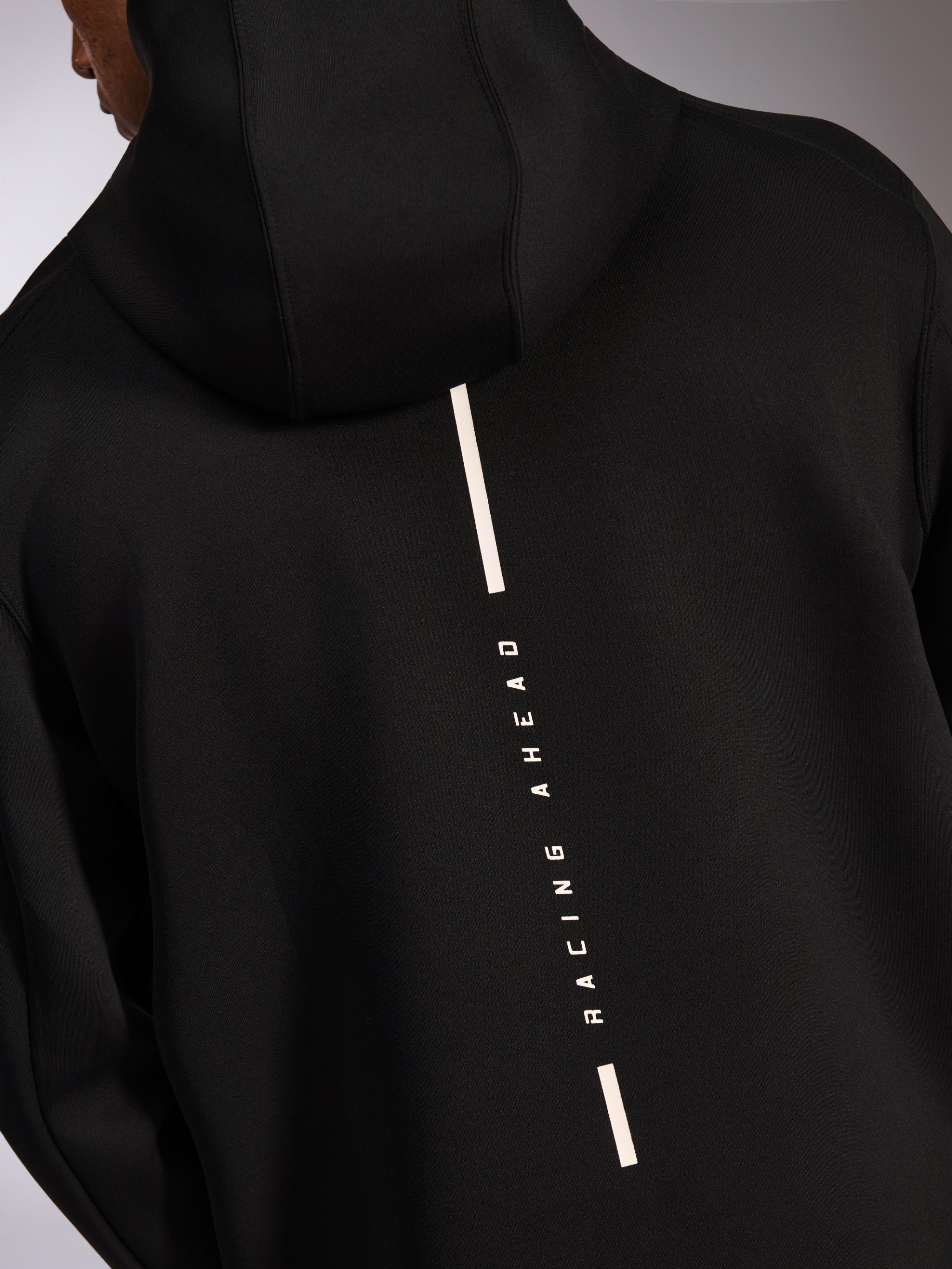 Alpinestars Insight Hoodie, sportowa bluza z kapturem, czarna, widok z tyłu z pionowym białym logo Racing Ahead w formie paska, gładki dwustronny polar tri-blend, nowoczesny design inspirowany motorsportem