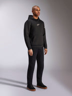 Alpinestars Insight Hoodie, czarna, casualowa bluza z polaru z kapturem, białe logo Astars na piersi, kieszeń typu kangur, noszona z czarnymi spodniami i sneakersami, ujęcie całej sylwetki w studio, streetwear inspirowany sportami motorowymi
