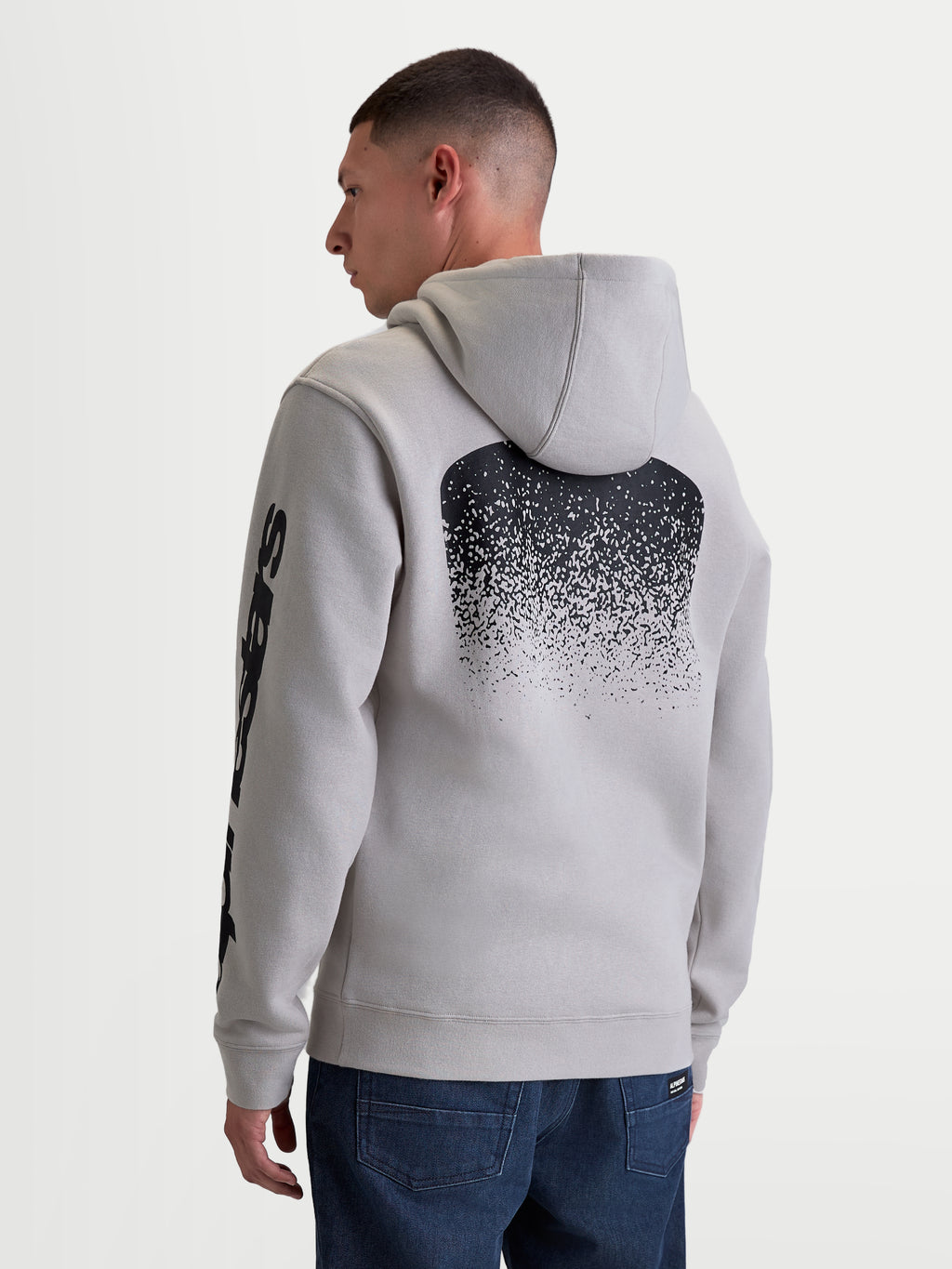 Alpinestars Bluza z kapturem Obsessed, męska bluza z kapturem typu polar, szara, z dużą czarną gradientową grafiką inspirowaną MX na plecach i brandingiem na rękawach, widok z tyłu na modelu, casualowa odzież sportowa w stylu motorsport.
