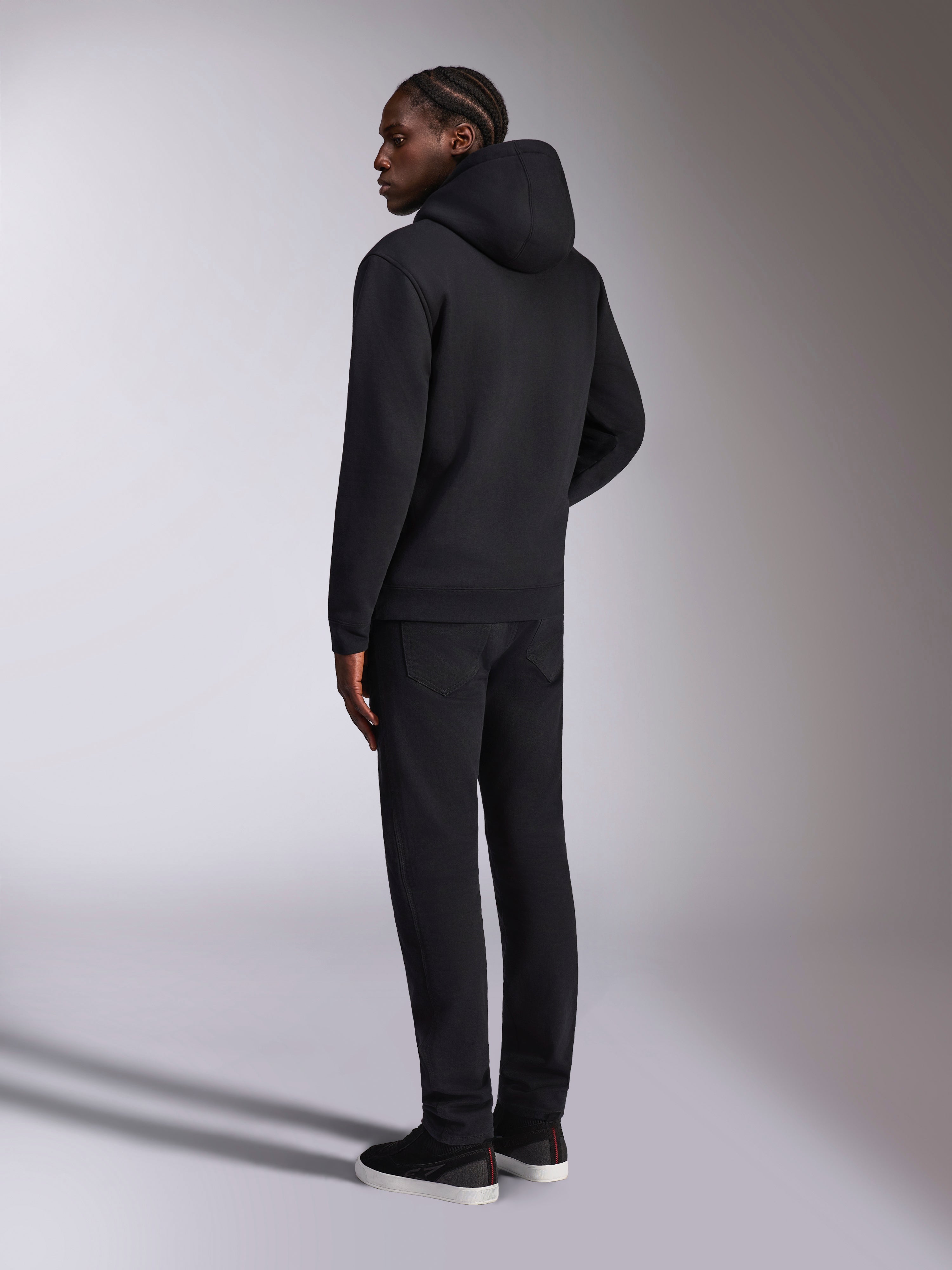 Alpinestars Pulse Hoodie, odzież streetwearowa, czarna, widok z tyłu na modela ubranego w gładką czarną bluzę z kapturem z polaru, minimalistyczny design ze ściągaczami na mankietach i na dole