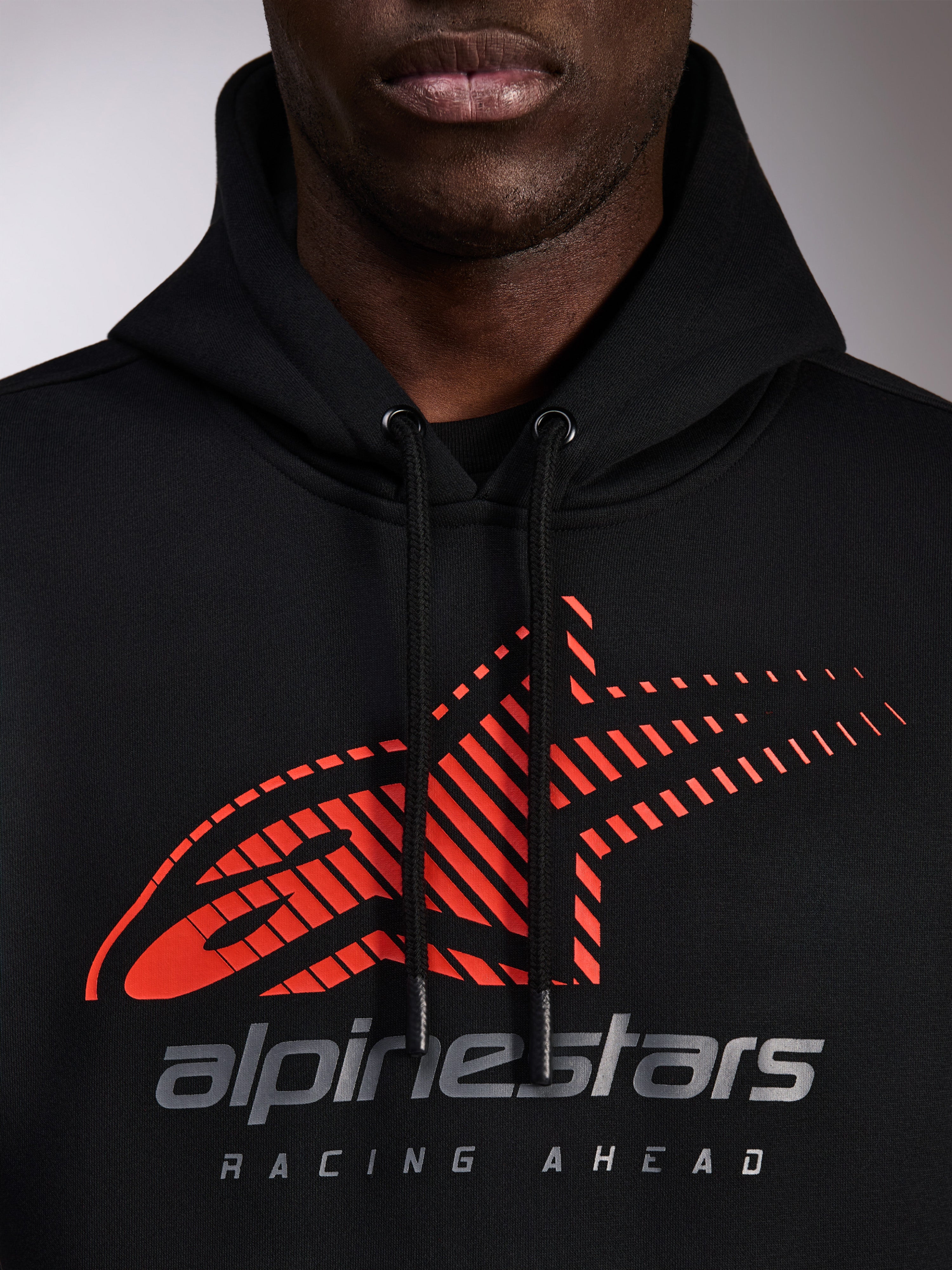 Alpinestars Pulse Hoodie, czarna bluza z kapturem, zbliżenie na klatkę piersiową z czerwonym logo Astars z efektem linii prędkości i srebrnym brandingiem, czarne sznurki z powlekanymi końcówkami, codzienna odzież streetwearowa w stylu motorsport