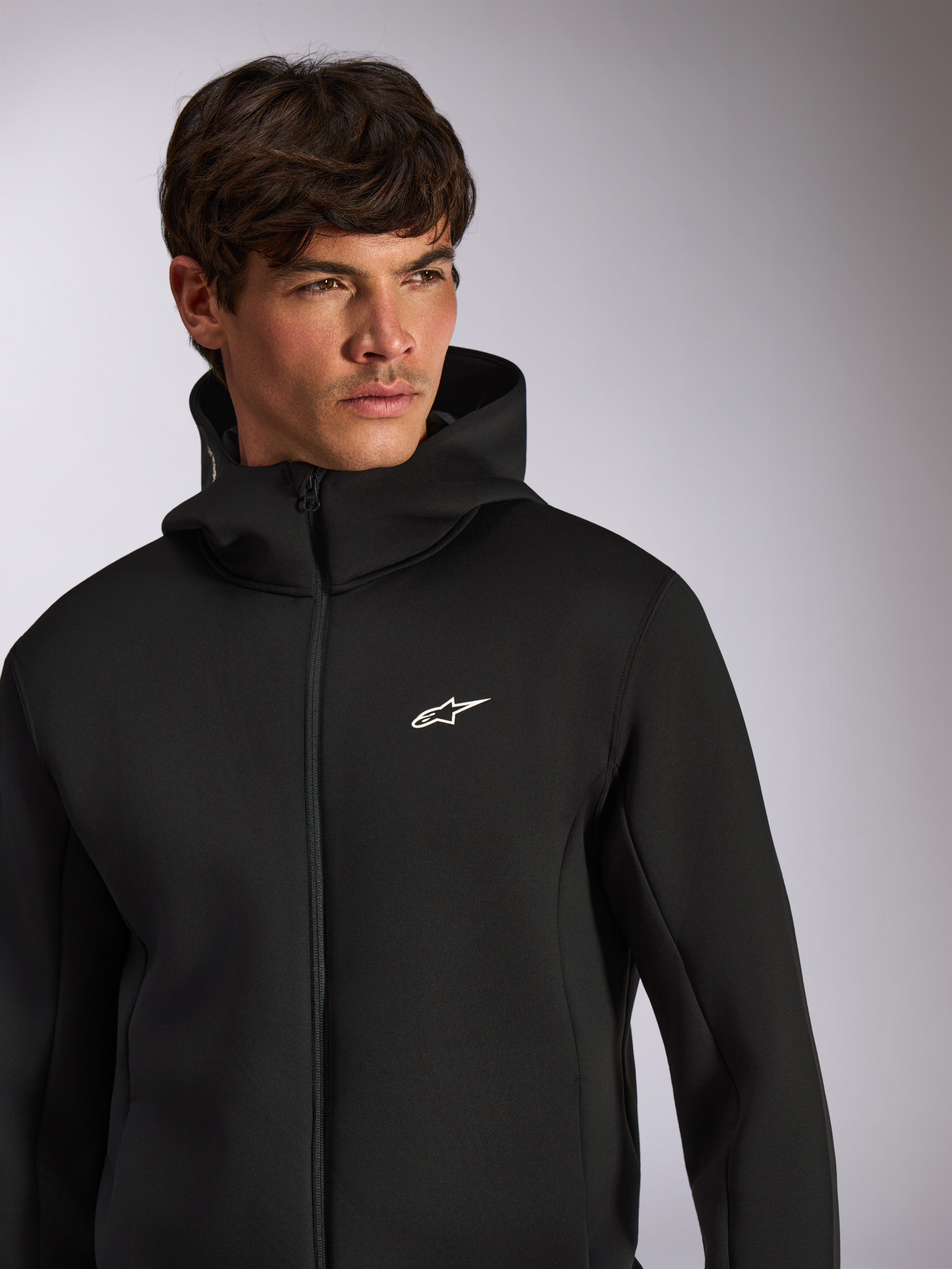Alpinestars Cypher Hoodie, codzienna odzież sportowa, czarna rozpinana bluza z kapturem z białym logo Astars na piersi, wysoki krój kaptura, prezentowana na modelu