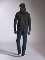 Alpinestars Cypher Hoodie, czarny dwustronny polar, widok z tyłu z małym białym logo Alpinestars na lewym biodrze, wysoki kaptur, połączona z ciemnoniebieskimi jeansami, casualowy streetwear inspirowany motorsportem