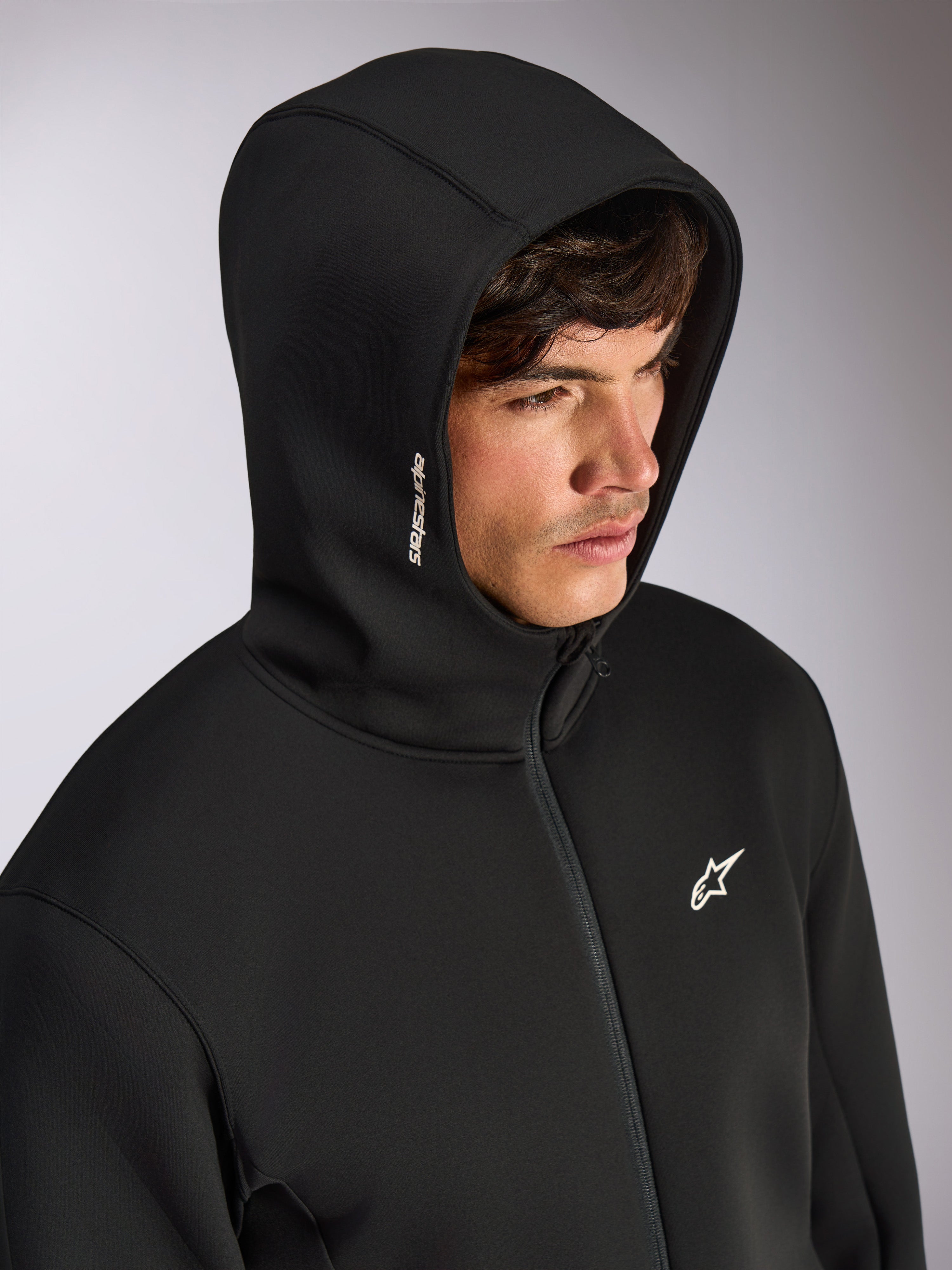 Alpinestars Cypher Hoodie, czarna bluza rozpinana z wysokim kapturem, biały napis Alpinestars na kapturze i logo gwiazdy na piersi, codzienna odzież uliczna inspirowana motorsportem