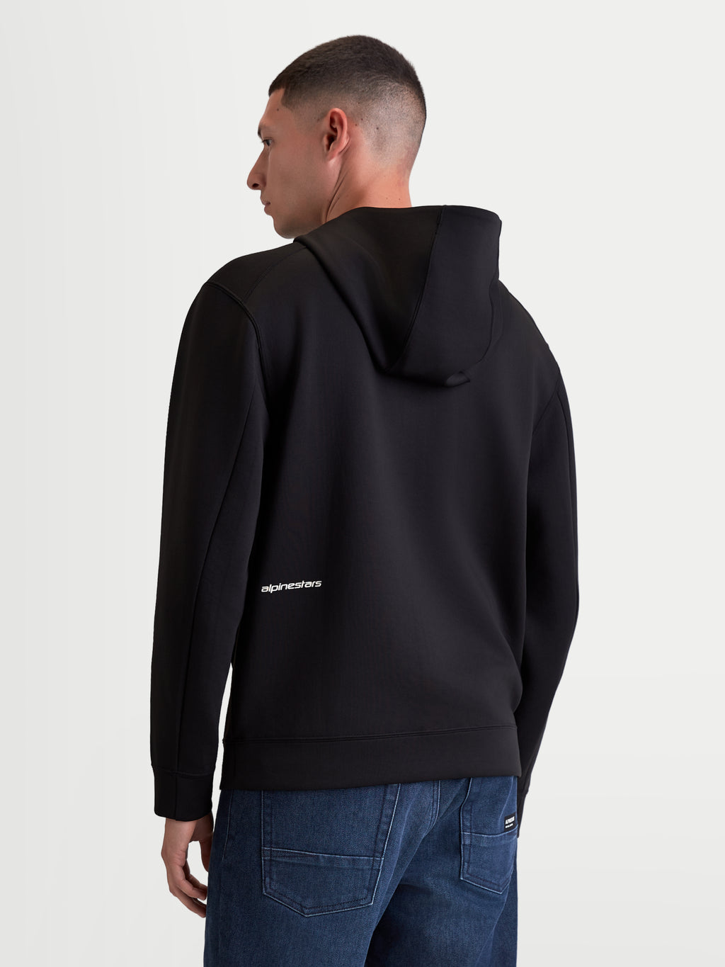 Alpinestars Bluza Z Kapturem Cypher, męska sportowa bluza rozpinana, czarny polar z materiału tri-blend, widok z tyłu na modelu, wysoki kaptur i białe logo Alpinestars na dole pleców, casualowa odzież sportowa.