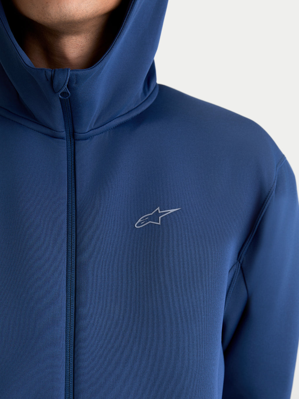 Alpinestars bluza z kapturem Cypher, sportowa bluza rozpinana dla kobiet i mężczyzn, stalowoniebieska, techniczna tkanina tri-blend, wysoki kołnierz z kapturem i logo Astars, widok z bliska na modelu.