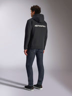 Alpinestars Transverse Hoodie, czarna rozpinana bluza z polaru, widok z tyłu z białym logotypem Alpinestars na plecach, zestawiona z ciemnoniebieskimi dżinsami i czarnymi sneakersami, codzienna odzież streetwearowa inspirowana sportami motorowymi