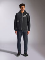 Alpinestars Transverse Hoodie, codzienna bluza polarowa rozpinana z przodu, czarna, białe logo Astars na piersi i nadruk „One Goal” z przodu, kaptur ze sznurkiem, w zestawieniu z ciemnymi jeansami i czarnymi sneakersami, lifestyle'owa odzież uliczna w stylu motorsport