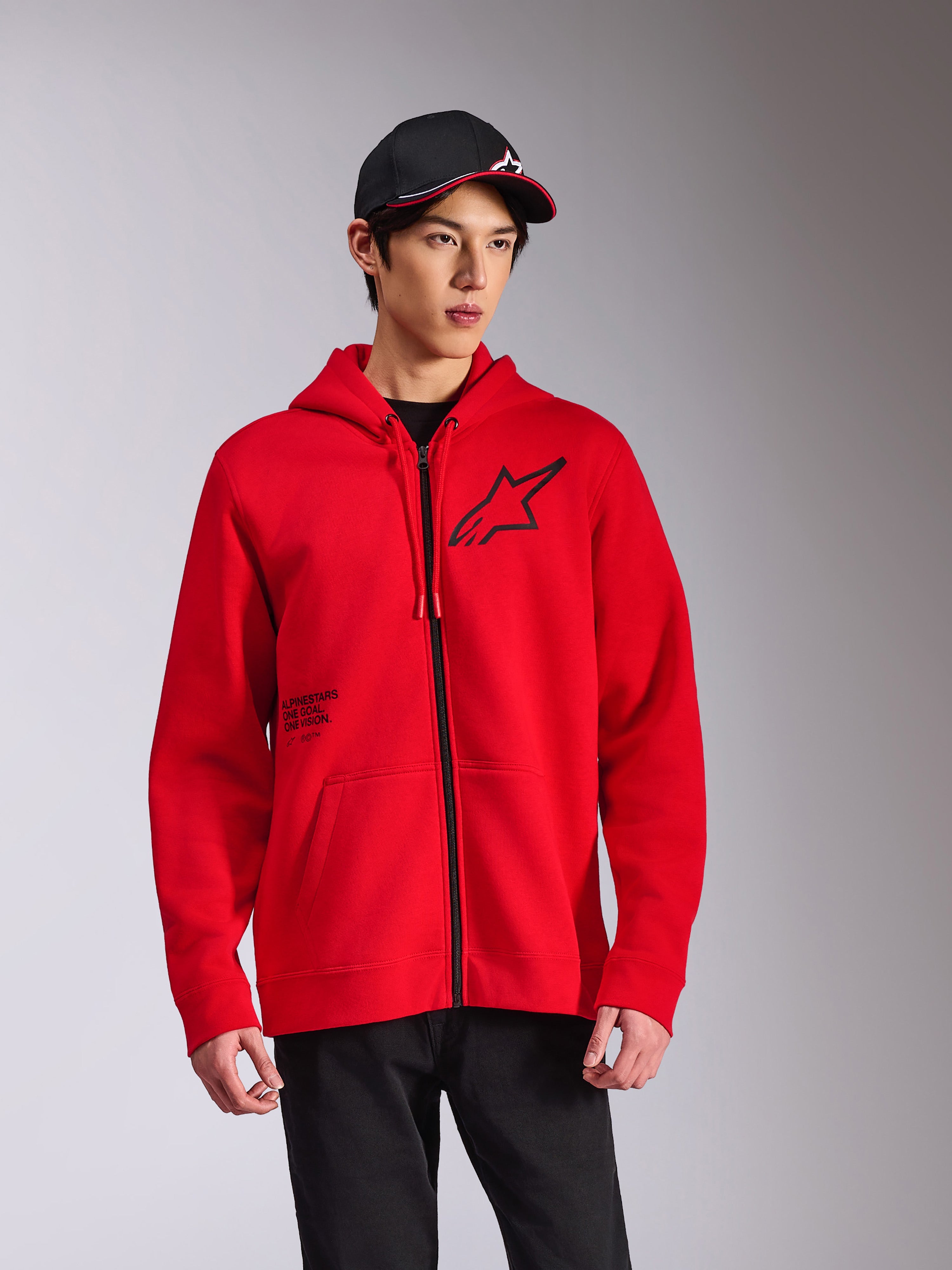 Alpinestars Transverse Hoodie, czerwona rozpinana bluza z kapturem z polaru, czarne logo Astars na piersi i nadruk 'One Goal', casualowy styl streetwearowy noszony z czarną czapką i spodniami