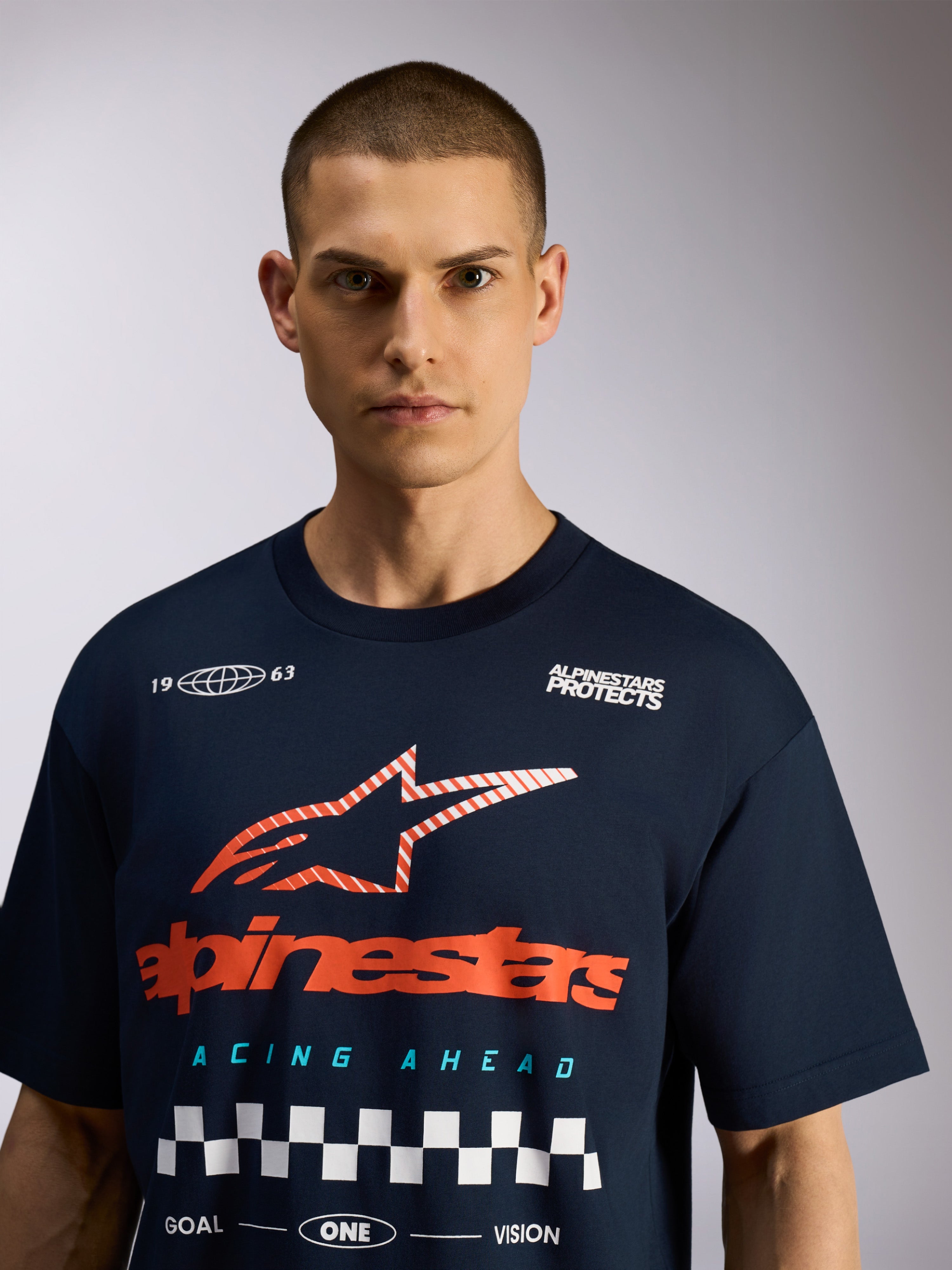 Alpinestars Aplomb Oversized CSF Tee, granatowa koszulka z krótkim rękawem, duża grafika na piersi z czerwonym logo i białą szachownicą, codzienny motorsportowy streetwear