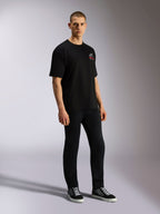 Alpinestars Overhang Oversized CSF Tee, czarny t-shirt z krótkim rękawem, biało-czerwone logo Astars z przodu, prezentowany przez modela w czarnych spodniach i sneakersach, luźny fason typu oversized w stylu streetwear