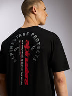 Alpinestars Overhang Oversized CSF Tee, czarna koszulka z krótkim rękawem, widok z tyłu z pionowym czerwonym logotypem Alpinestars i okrągłą grafiką „Alpinestars Protects”, codzienna odzież uliczna inspirowana sportami motorowymi
