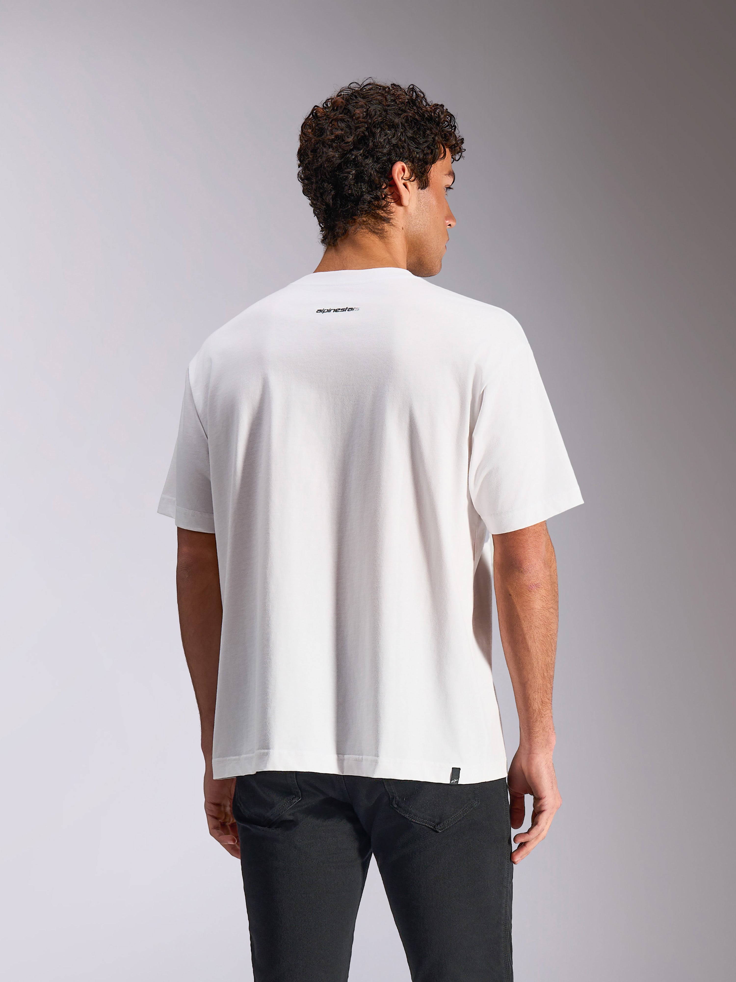 Alpinestars Focused Oversized CSF Tee, biała koszulka z krótkim rękawem, widok z tyłu na modelu pokazujący małe czarne logo Alpinestars poniżej linii karku, luźny krój typu oversized, codzienny styl streetwearowy