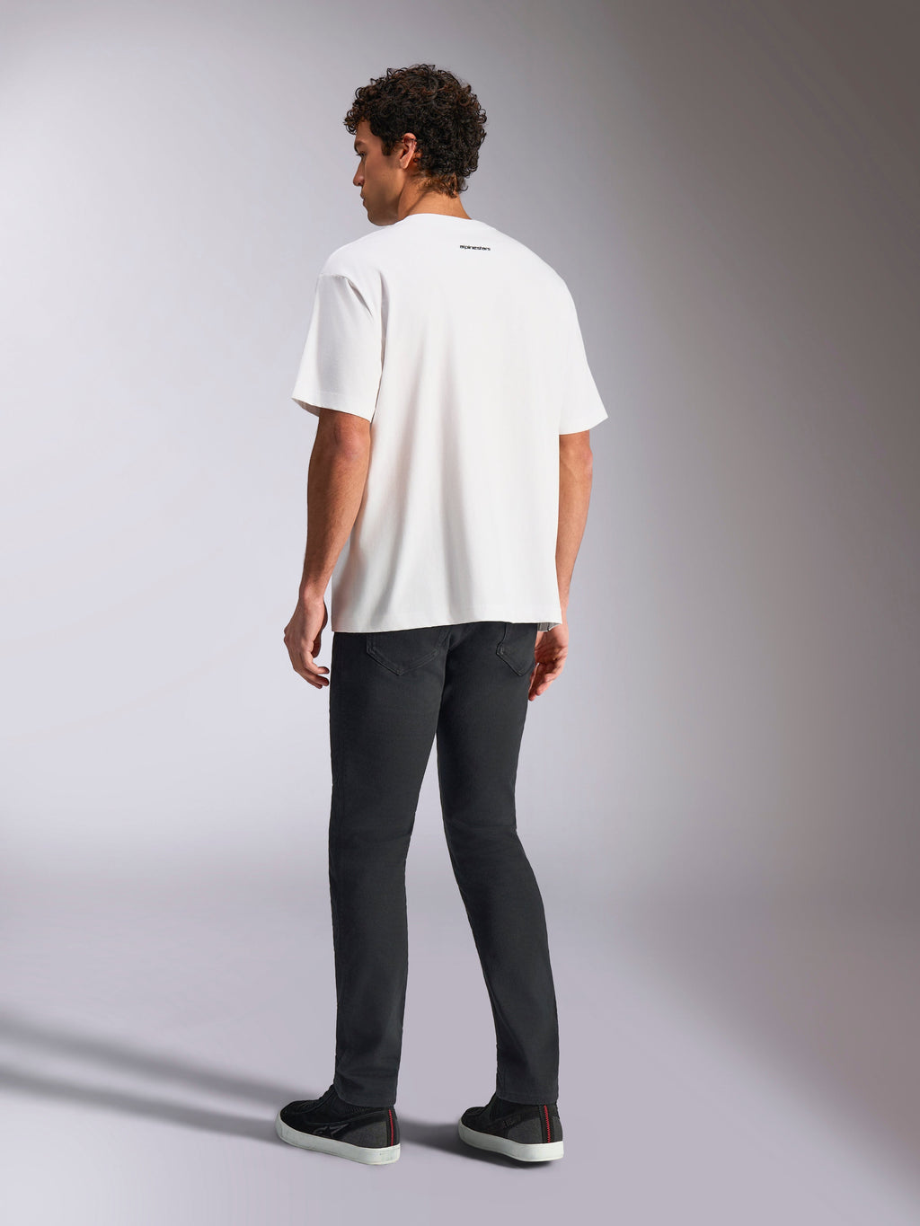 Alpinestars Focused Oversized CSF Tee, koszulka z krótkim rękawem, biała, mały czarny napis Alpinestars na karku, zestawiona z czarnymi spodniami, krój oversized, casualowy streetwear inspirowany motorsportem