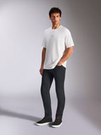 Alpinestars Focused Oversized CSF Tee, biała koszulka z krótkim rękawem, z małym czarnym logo Astars na piersi, prezentowana przez modela w ciemnych spodniach i czarnych sneakersach, codzienna odzież uliczna inspirowana motorsportem