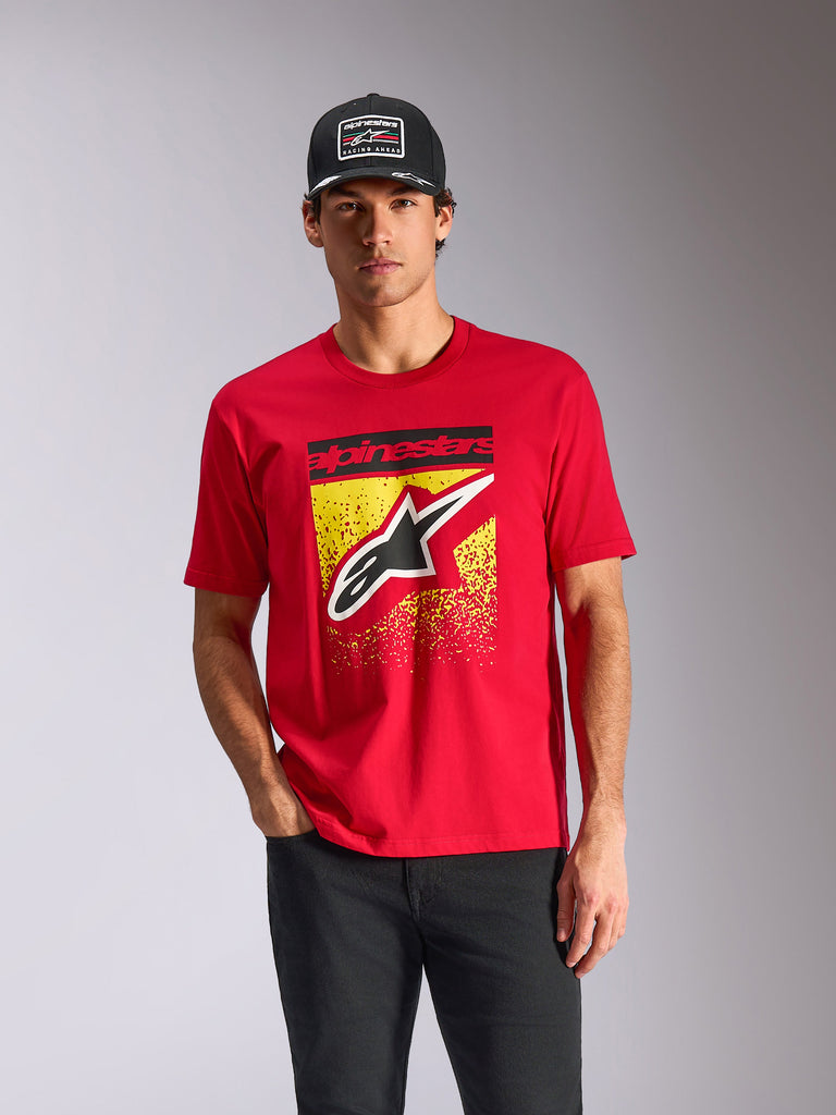 Alpinestars Noka CSF Tee, koszulka z krótkim rękawem, czerwona, logo Astars z przodu z żółtą gradacją MX, prezentowana przez modela w czarnej czapce Alpinestars, streetwear w stylu motorsport