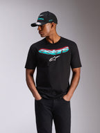 Alpinestars Ellipsoid CSF Tee, koszulka z krótkim rękawem, czarna, turkusowo-różowy gradient napisu Astars i białe logo, noszona przez modela z pasującą czapką Alpinestars i czarnymi jeansami, casualowy motorsportowy streetwear