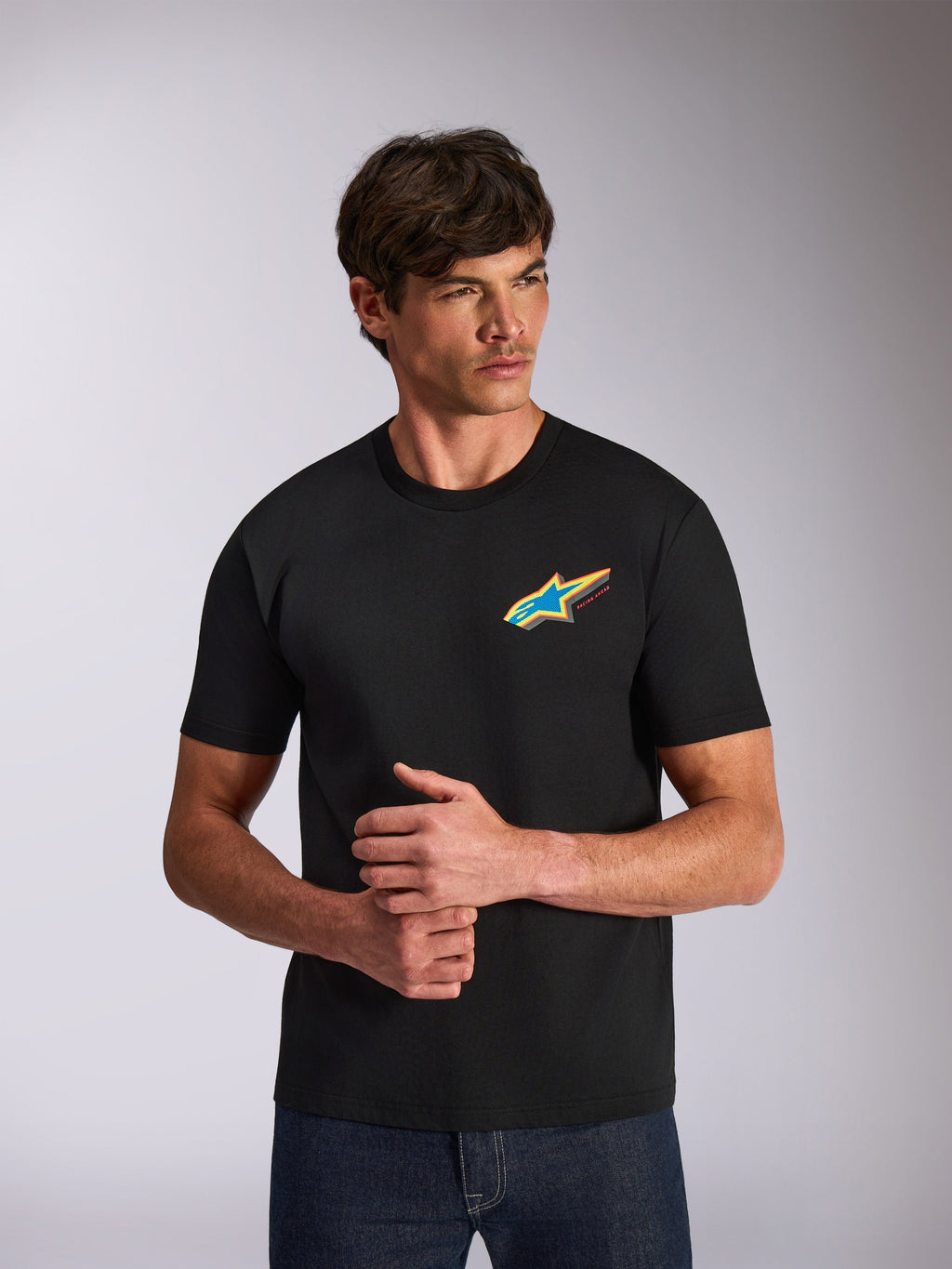 Alpinestars Angler CSF Tee, koszulka z krótkim rękawem, czarna, żywe wielokolorowe logo gwiazdy Astars na piersi, codzienna odzież streetwearowa inspirowana motorsportem, model prezentujący produkt