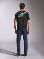Koszulka Alpinestars Angler CSF Tee, t-shirt z krótkim rękawem, czarny, widok z tyłu na modela ubranego w koszulkę z dużym, wielokolorowym logo Astars i napisem „RACING AHEAD”, w połączeniu z ciemnoniebieskimi dżinsami, codzienna odzież uliczna w stylu motorsportowym