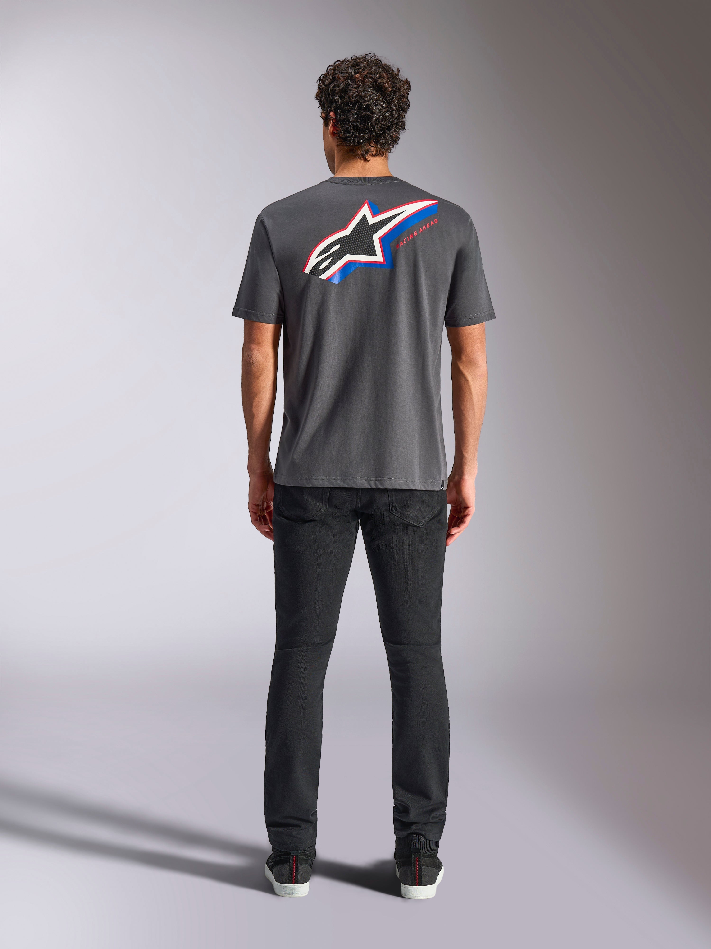 Koszulka Alpinestars Angler CSF, T-shirt z krótkim rękawem, grafitowy, duże wielokolorowe logo Astars na plecach z czerwonymi i niebieskimi akcentami, widok z tyłu na modelu, codzienna odzież streetwearowa w stylu motorsport