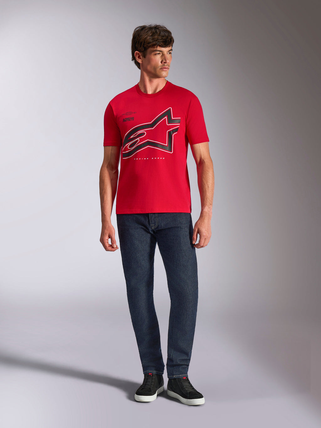 Alpinestars Authority CSF Tee, czerwona koszulka z krótkim rękawem, duże czarne przycięte logo Astars z białym konturem, zestawiona z ciemnoniebieskimi jeansami i czarnymi sneakersami, codzienna odzież streetwear inspirowana motorsportem