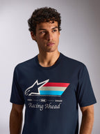 Alpinestars Trifecta CSF Tee, koszulka z krótkim rękawem, granatowa, białe logo Astars z trójkolorowymi paskami i napisem „Racing Ahead”, lifestylowe ujęcie w klimacie motorsportu