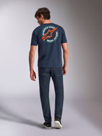 Alpinestars Aorbit CSF Tee, koszulka z krótkim rękawem, granatowa, widok z tyłu na modelu z dużą okrągłą grafiką, czerwone logo Astars i napis „Always Fast Made to Last”, casualowy streetwear motorsportowy