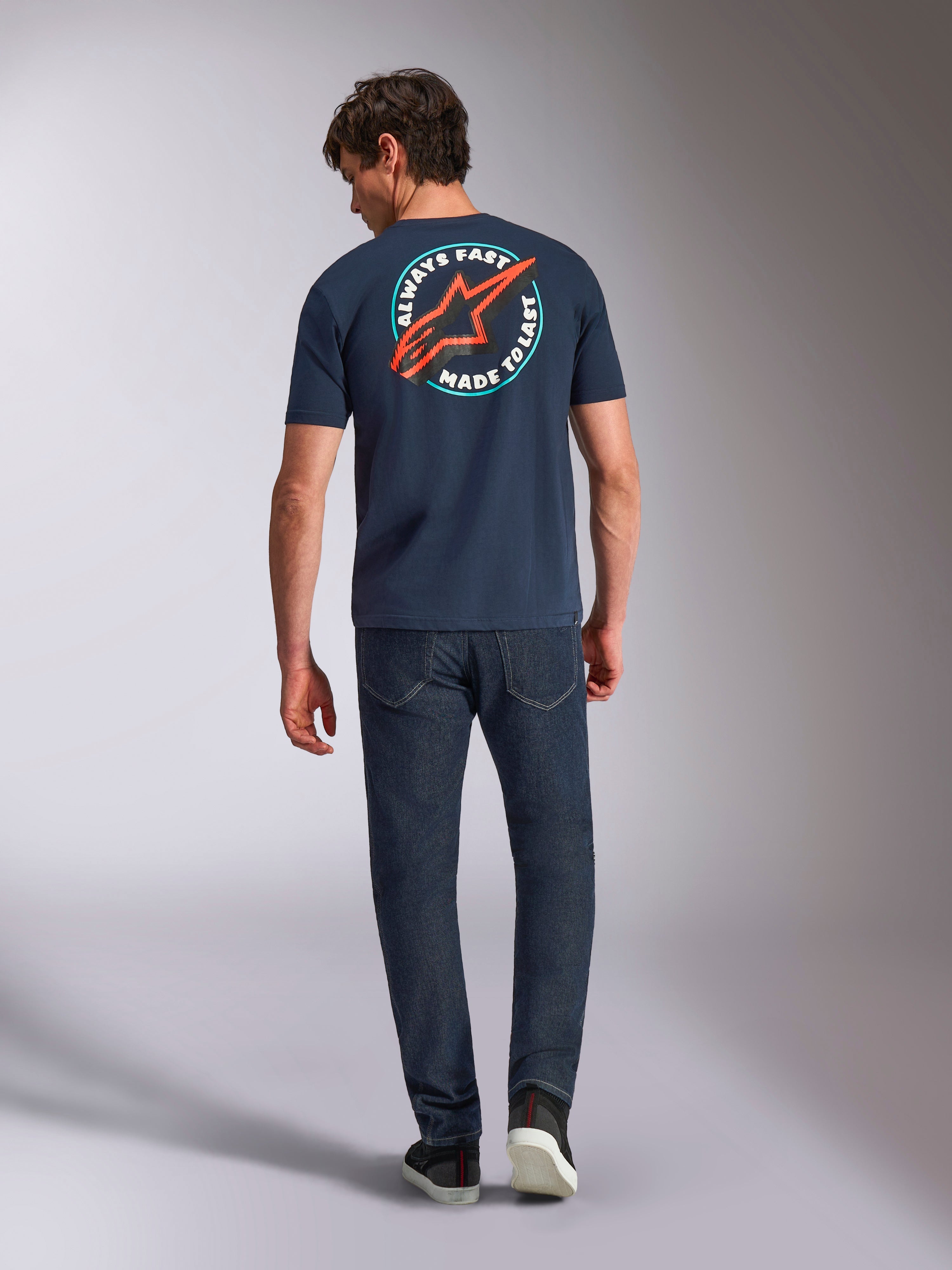 Alpinestars Aorbit CSF Tee, koszulka z krótkim rękawem, granatowa, widok z tyłu na modelu z dużą okrągłą grafiką, czerwone logo Astars i napis „Always Fast Made to Last”, casualowy streetwear motorsportowy