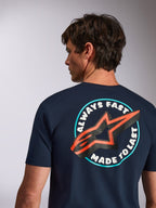 Alpinestars Aorbit CSF Tee, granatowa koszulka z krótkim rękawem, widok z tyłu z grafiką Always Fast Made to Last i pomarańczowym logo gwiazdy, casualowa odzież motorsportowa