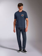 Alpinestars Aorbit CSF Tee, granatowa koszulka z krótkim rękawem, okrągła grafika na piersi z napisem Always Fast Made to Last, noszona z ciemnymi jeansami i sneakersami, codzienna odzież lifestylowa w stylu motorsport