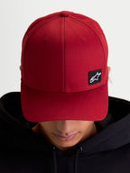Alpinestars czapka Pivot, sportowa czapka z daszkiem typu baseball cap, ciemnoczerwona, unisex, zakrzywiony daszek i usztywniona korona, mała czarna haftowana naszywka z logo Astars na trwałej tkaninie keprowej, widok na modelu.
